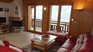 A cozy living room with a fireplace, red leather sofa, and a television. - Hilltop Apartment With Views (Veysonnaz)