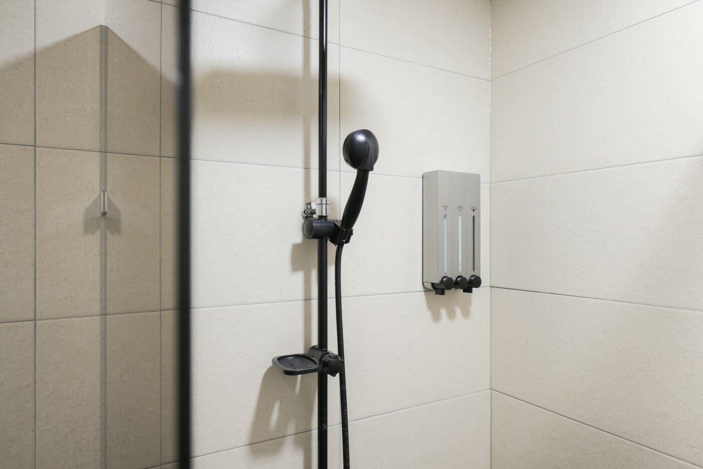 Ducha con cabezal de ducha de mano, panel de control en la pared y un accesorio de ducha manual.