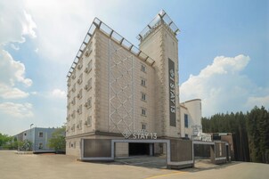 Un hotel de diseño moderno, con un llamativo letrero 'STAY 13', varios balcones y un área de estacionamiento.