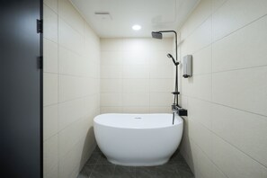 Une salle de bain moderne dotée d’une baignoire sur pieds, d’un pommeau de douche à main et d’un panneau de commande fixé au mur.