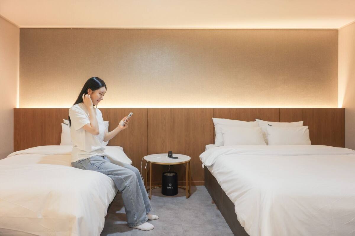 Een hotelkamer met twee bedden, een nachtkastje en een prullenbak.