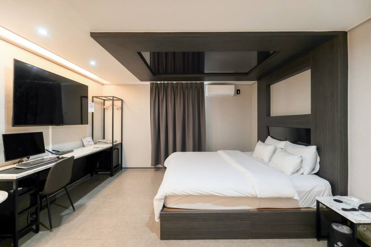 Een moderne hotelkamer met een bed, bureau en een groot flatscreen-televisie.