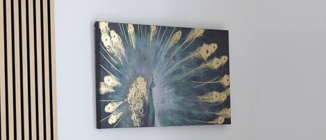 A wall-mounted artwork depicting a peacock with a dark background and golden feathers.