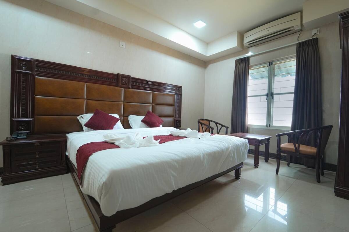 Una habitación de hotel con una cama grande, una mesita de noche, un escritorio y una silla.