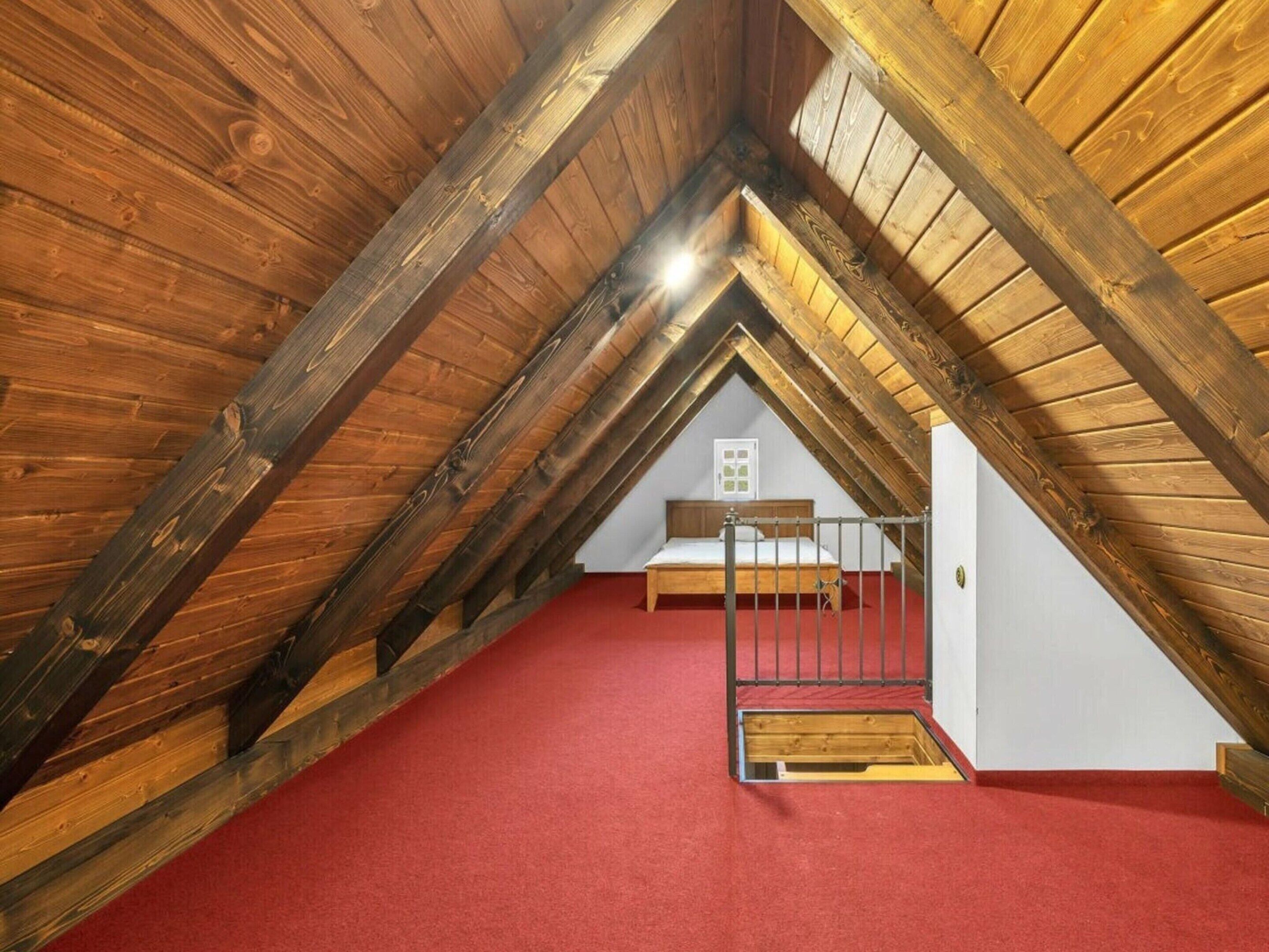 An attic bedroom with a sloped ceiling, a bed, and a window.