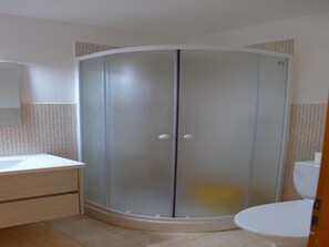 A bathroom with a glass-enclosed shower, a toilet, and a sink with a cabinet. - 2-room Apartment in Veysonnaz (Veysonnaz)