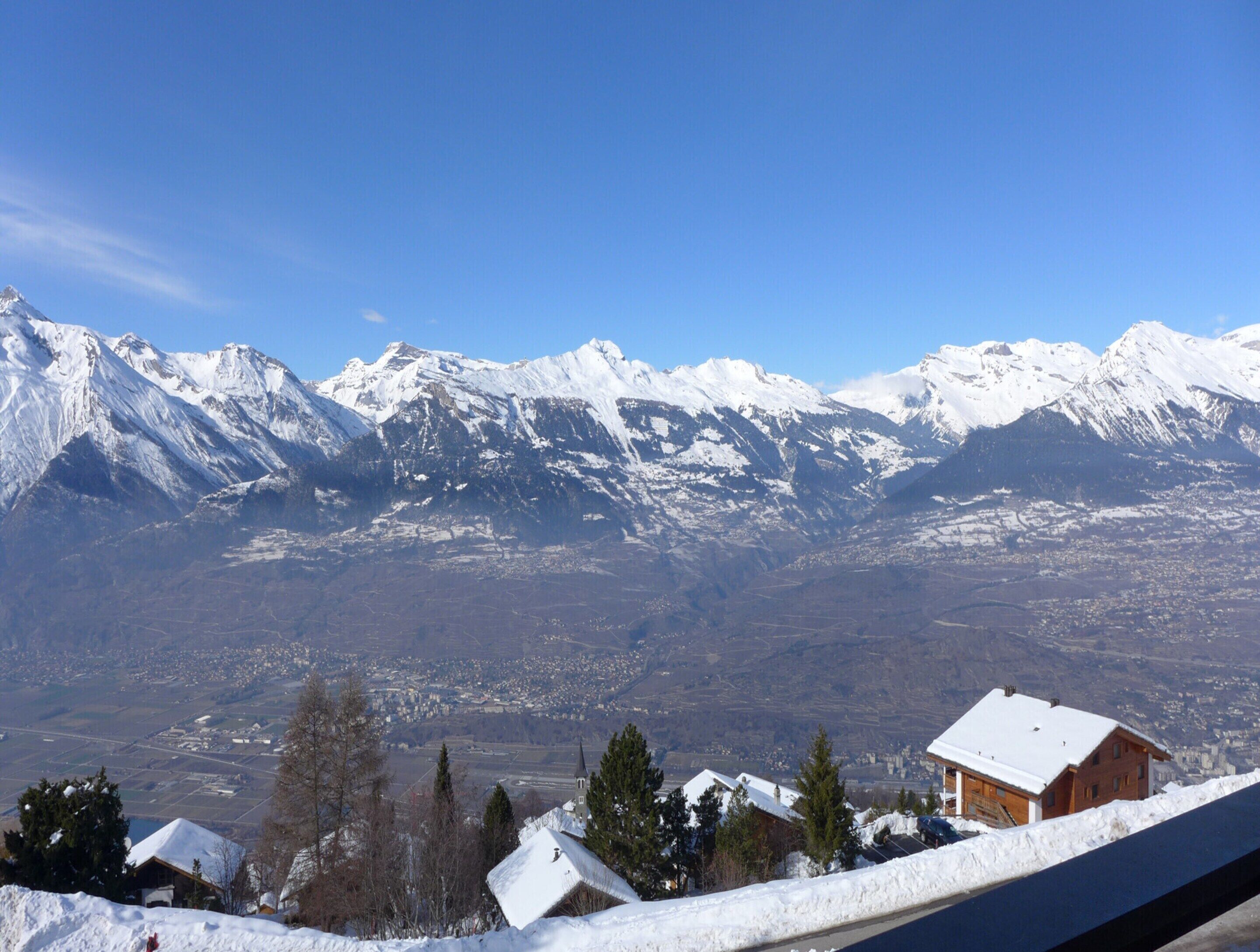 Eine Berglandschaft mit schneebedeckten Gipfeln und einer Stadt im Tal.