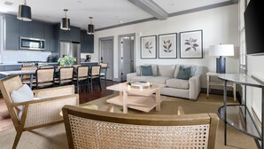 A modern living room with a sofa, coffee table, and wicker chairs. - Rosemary House - C | Perfect for Weddings + Events (Charleston)