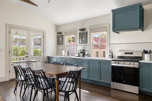 Una cocina con una mesa, sillas, estufa y armarios.