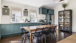 Una cocina moderna con armarios color esmeralda, una mesa de comedor de madera y sillas negras.