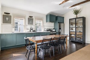 Una cocina con mesa y sillas, armarios verdes y una vitrina con vajilla.