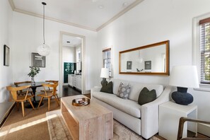 A modern living room with a sofa, coffee table, and dining area. - Harleston House | Unit B | Sleeps 6 (Charleston)