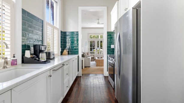 A narrow kitchen with white cabinets, a stainless steel refrigerator, and a coffee maker on the counter. - Harleston House, Unit B, Sleeps 6 (Charleston)