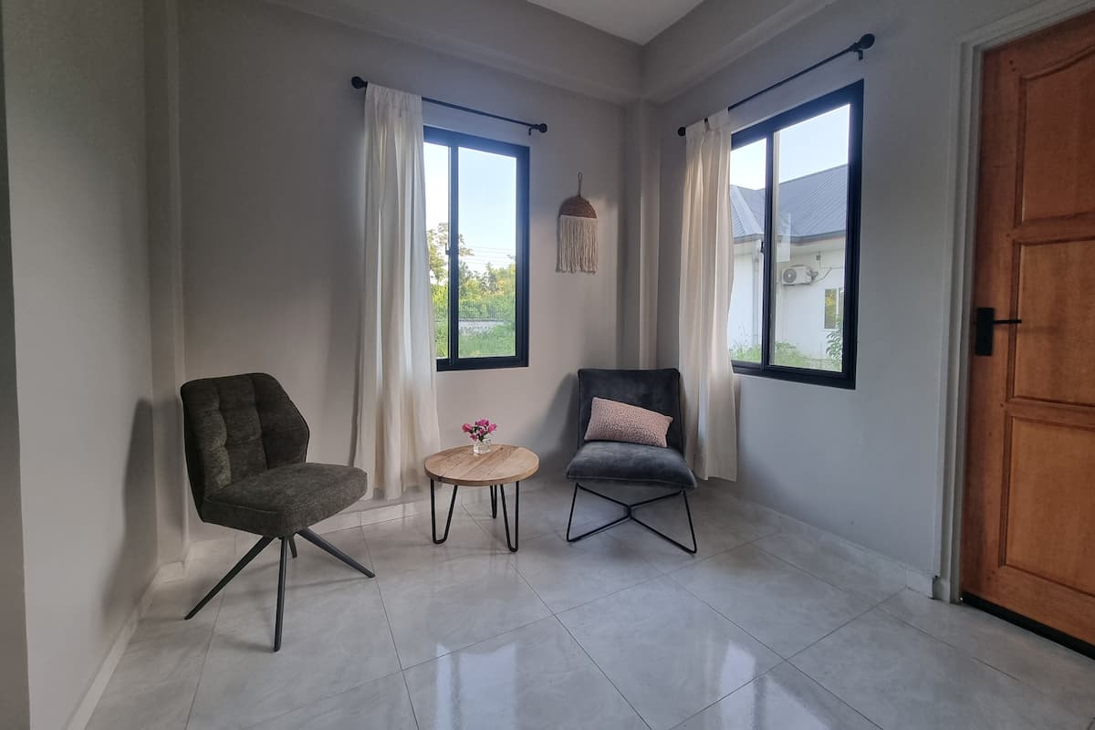 Ein Zimmer mit zwei Stühlen, einem kleinen Tisch und einer Holztür.