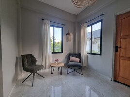 Una habitación con dos sillas, una mesita y una puerta de madera.