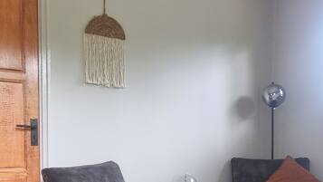 A modern living room with two grey armchairs, a wooden door, a hanging light fixture, and a floor lamp.