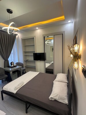 A hotel room with a bed, a desk, a chair, a television, a wardrobe, and a mirror. - new arcadia taksim (Istanbul)
