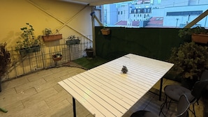 A rooftop terrace with a white table, chairs, potted plants, and a view of buildings. - new arcadia taksim (Istanbul)