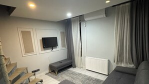 A modern bedroom with a large bed, a TV mounted on the wall, a staircase, and a radiator. - new arcadia taksim (Istanbul)
