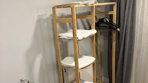 A wooden shelf unit with multiple shelves, a hanging rack, and a metal chair. - new arcadia taksim (Istanbul)