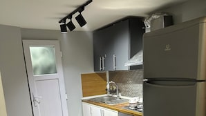 A compact kitchen with a refrigerator, a sink, and a dining area with a table and chairs. - new arcadia taksim (Istanbul)