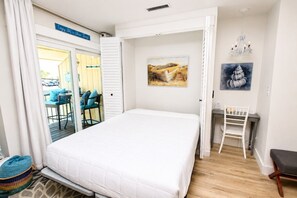 Een slaapkamer met een bed, een bureau, een stoel en een schilderij aan de muur.