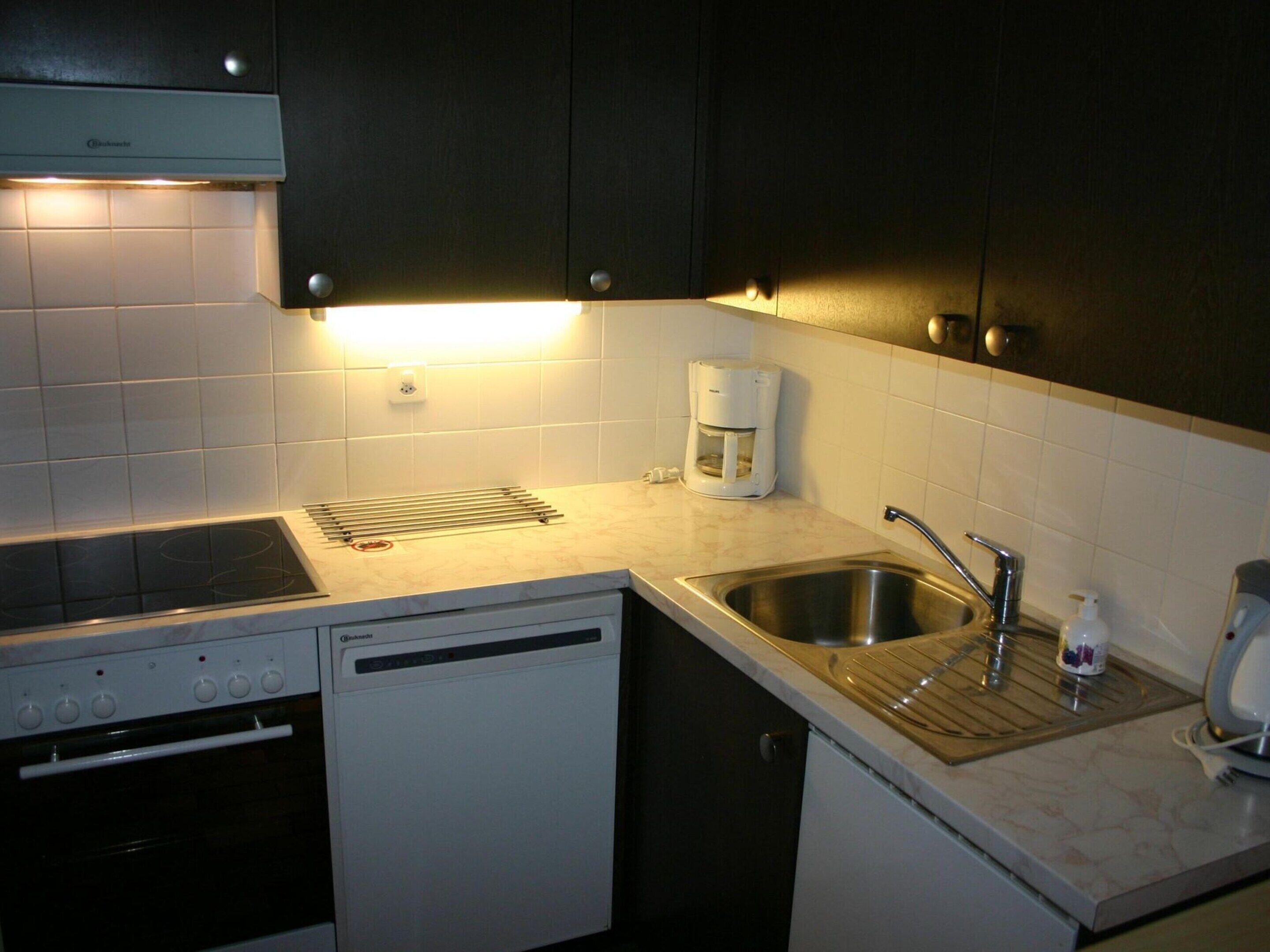 A compact kitchen with a dishwasher, a coffee maker, and a sink.