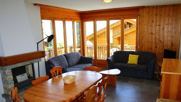 Un interior de madera con una mesa de comedor, sillas, un sofá y una chimenea.