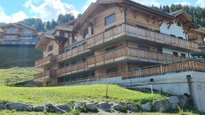 Ein mehrstöckiges Holzchalet mit Balkonen vor einer Bergkulisse.