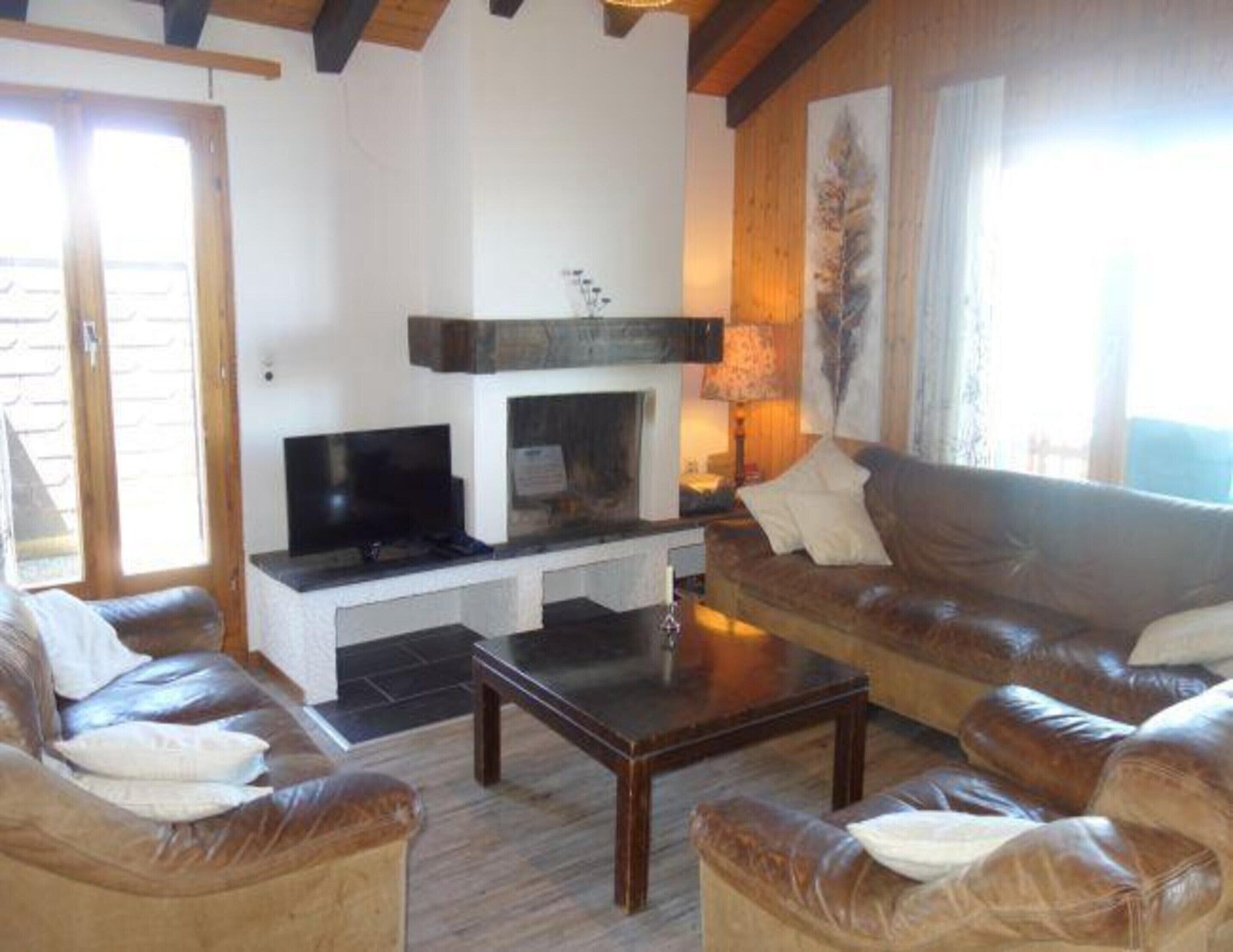 A living room with a fireplace, leather sofas, a coffee table, and a television.
