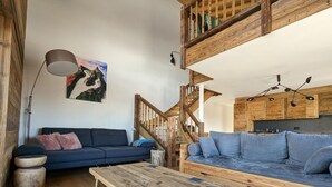 Ein rustikales Wohnzimmer mit einer hölzernen Bank, zwei Sofas, einer Treppe und einer Küchenzeile.