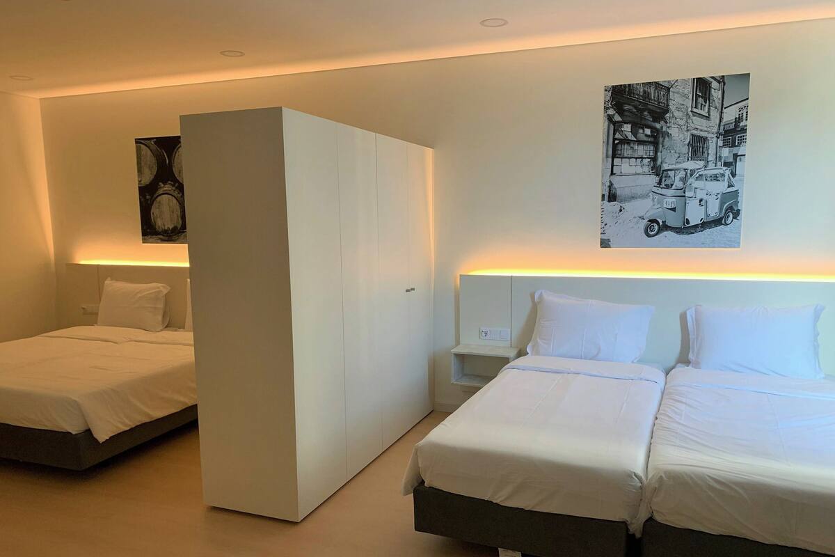 A modern hotel room with two single beds, a large wardrobe, and a nightstand with a lamp.
