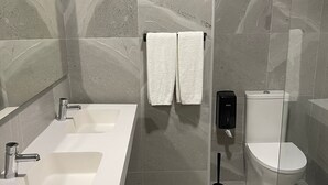 A modern bathroom with a large sink, two towel racks, a toilet, and a handheld bidet. - Hotel Areosa (Maia)