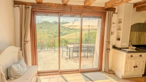 A room with a sliding glass door leading to an outdoor patio with a table and chairs. - La Ferme, Gîtes for 8 people (Puycalvel)