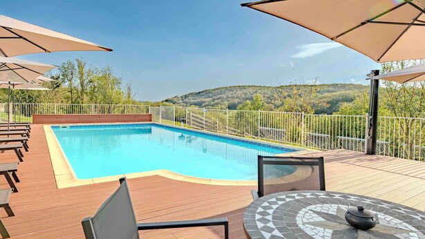A swimming pool with a wooden deck, outdoor seating, and umbrellas. - La Ferme, Gîtes for 8 people (Puycalvel)