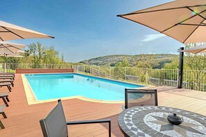 A swimming pool with a wooden deck, outdoor seating, and umbrellas. - La Ferme, Vacation Homes for 8 People (Puycalvel)