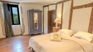A bedroom with a large bed, a wardrobe, a mirror, and a window with curtains. - La Ferme, Gîtes for 8 people (Puycalvel)