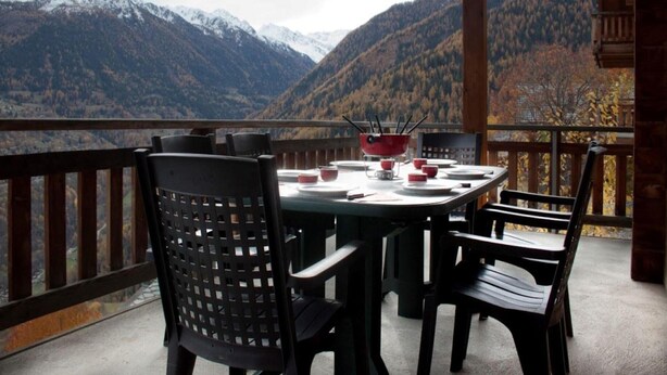 Een eethoek met een tafel gedekt voor vier personen, met uitzicht op een bergachtig landschap.