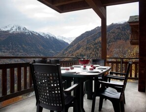 A dining area with a table set for four, overlooking a mountainous landscape. - Spacious Chalet Amidst Mountains (Nendaz)