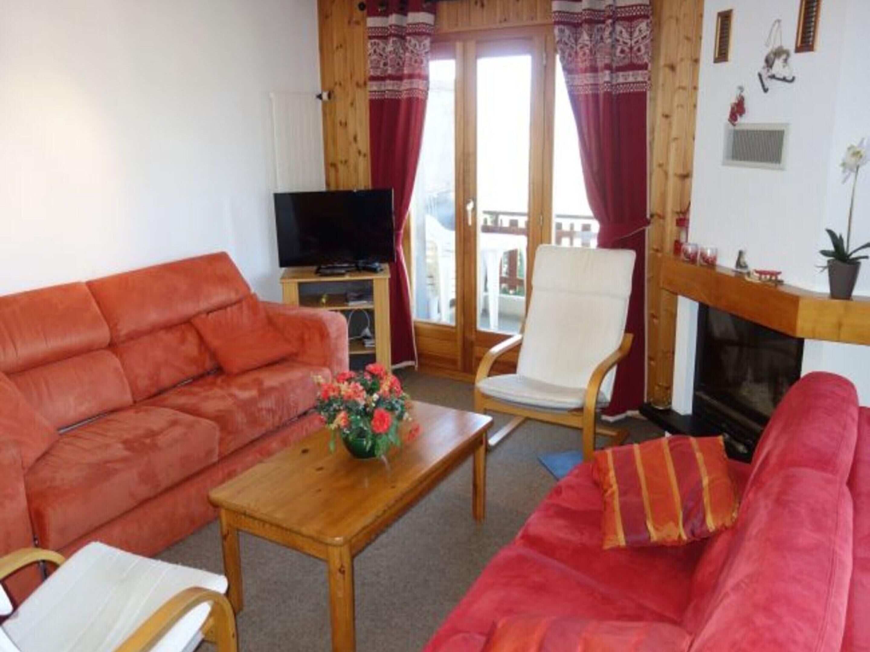 A living room with a red sofa, a white armchair, and a wooden coffee table.