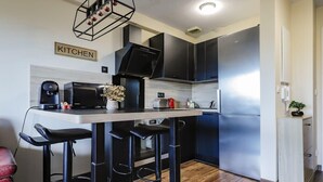 A modern kitchen with a bar stool area, a stainless steel refrigerator, and a coffee machine. - Montaigne - Proche Tram - 5min Aéroport (Blagnac)