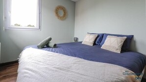 A bedroom with a bed, a window, and a wall-mounted decorative item. - Montaigne - Proche Tram - 5min Aéroport (Blagnac)