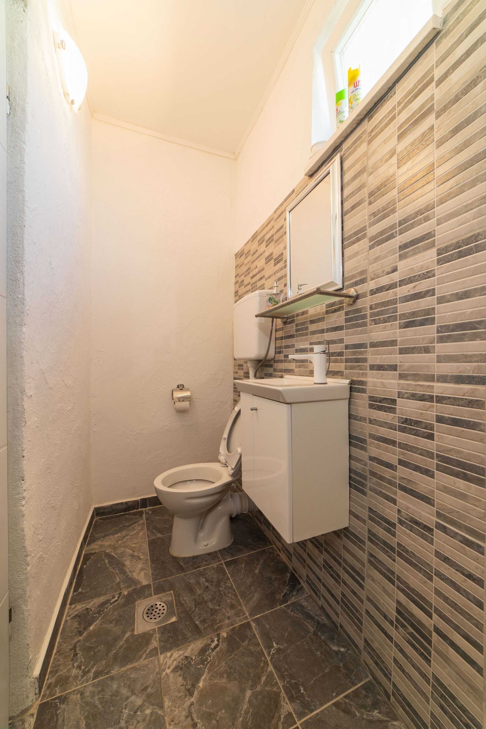 A bathroom with a toilet, a sink, and a mirror.