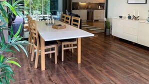 Eine moderne Küche mit weißen Schränken und einem Essbereich mit einem weißen Tisch und Holzstühlen.