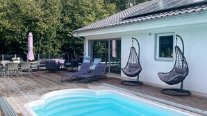 Ein Schwimmbecken mit Liegestühlen und einer Sonnenterrasse.