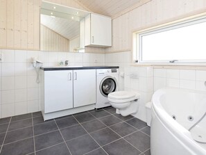 A modern bathroom with a washing machine, toilet, and bathtub. - Nice Holiday Home for 8-persons (Grossenbrode)