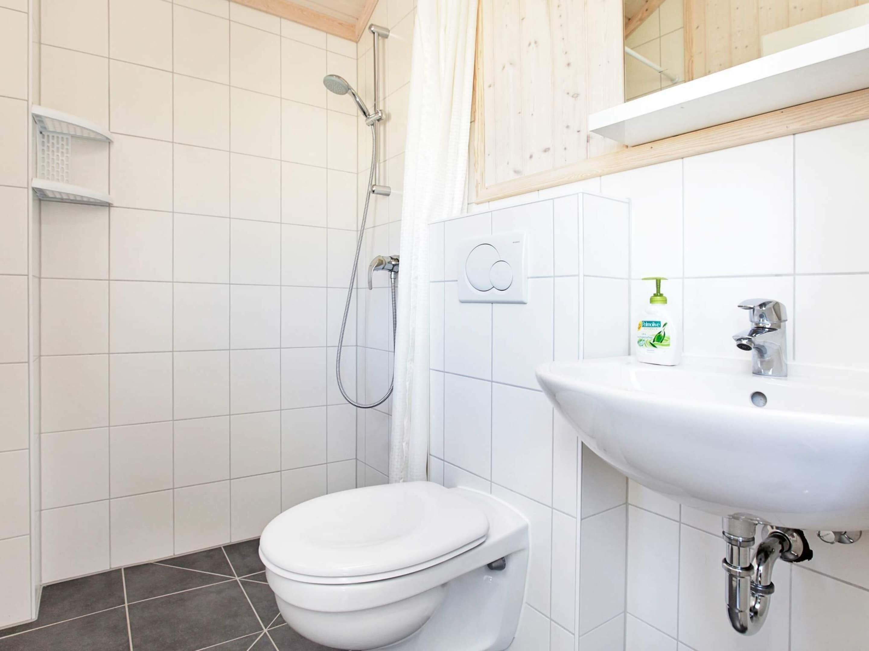 A bathroom with a toilet, a shower, and a sink.