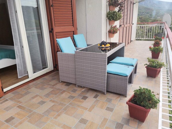 Un balcon avec un canapé en osier, une petite table et des plantes en pot.