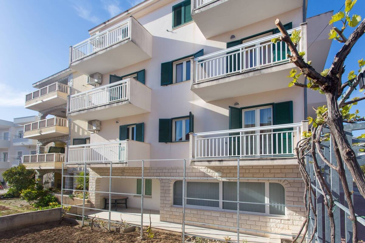 Un edificio residencial de varios pisos con balcones, fachada de ladrillo y cielo despejado.