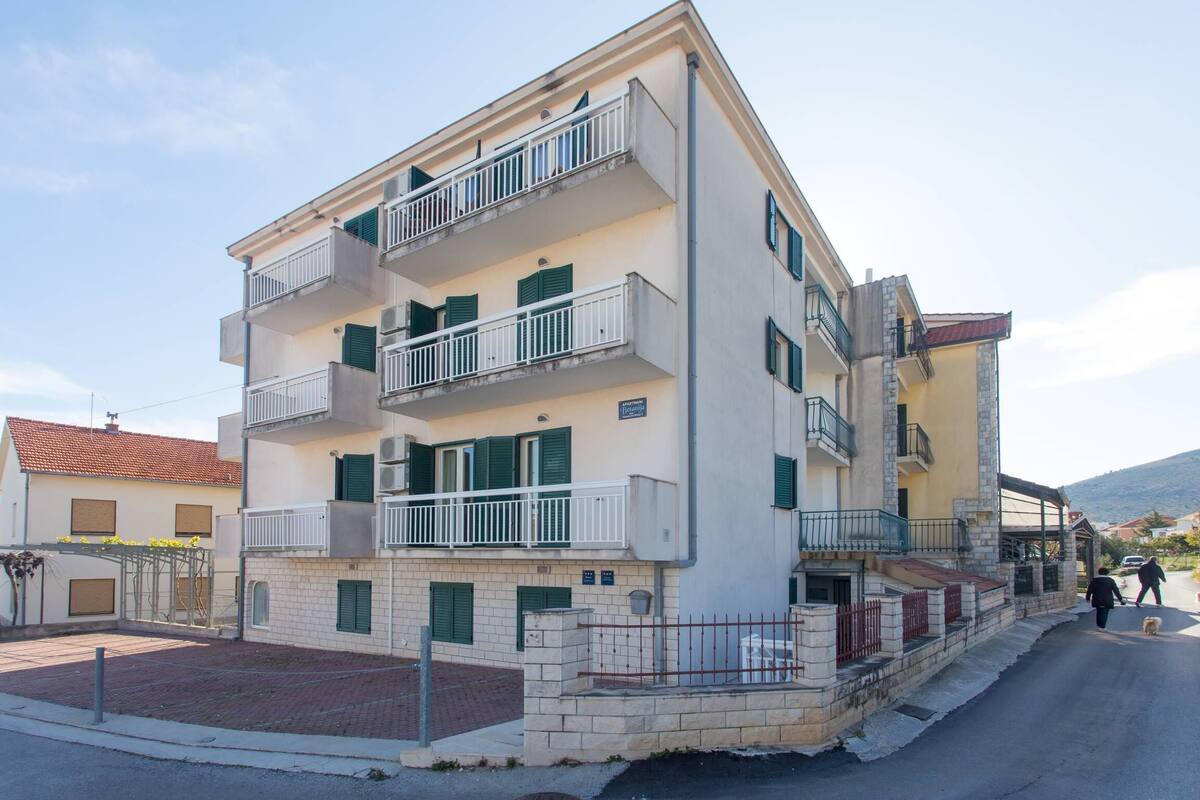 Un edificio residencial de varios pisos con balcones, fachada de ladrillo y una calle pavimentada frente a él.